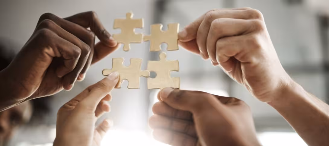 a group of hands, presumably attached to people, coming together to make a puzzle